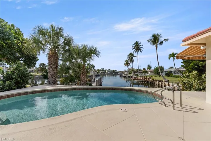Swimming pool featuring a water view, a patio area, and a boat dock