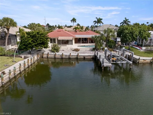 Dock area featuring boat lift, a water view, a patio, and an outdoor pool