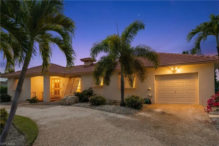View of front of property with a garage, driveway, a tile roof, and stucco siding