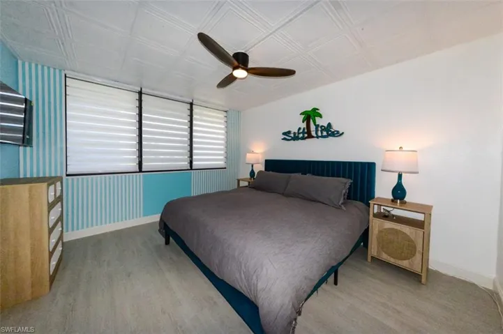 SOUTHERN EXPOSURE GUEST BEDROOM.  LUXURY VINYL PLANK TILE FLOORING.  FLUTED WOOD ACCENT WALL.  CUSTOM ZEBRA BLINDS.  PVC CEILING TILE.  REMOTE CONTROLLED CEILING FAN W/LIGHT.