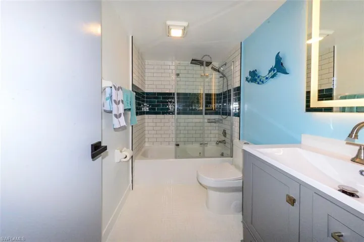 GUEST BATH.  REFURBISHED TUB.  SHOWER HAS FULL-HEIGHT TILE WALLS W/DECORATIVE TILE ACCENT.  MODERN TOILET.