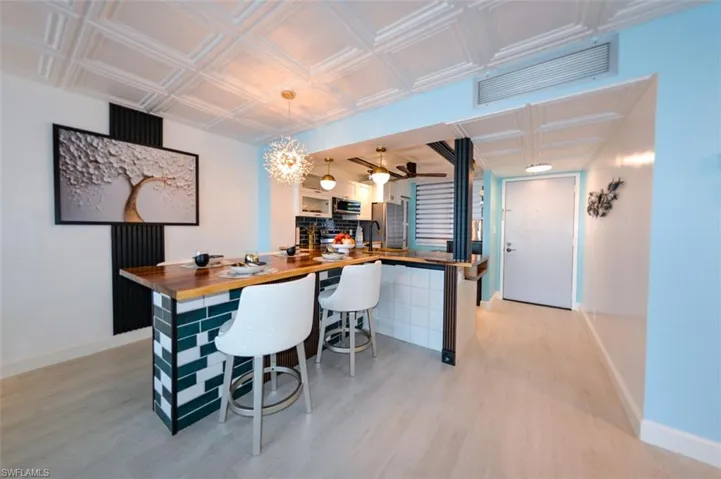 ACACIA BUTCHER BLOCK COUNTER-HEIGHT DINING EXTENSION.  TILE ACCENTED.  FLUTED WOOD PANEL FRAMES DECORATIVE ART WORK.