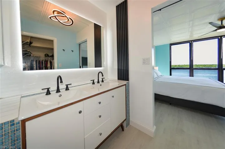 OWNER'S SUITE BATH.  DUAL SINK VANITY W/TILE ACCENTS.  BACKLIT ANTI-FOG MIRROR.  FLUTED WOOD ACCENT PANEL.