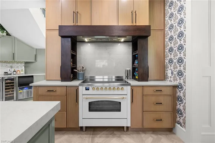 Gourmet kitchen featuring a white range, custom wood cabinetry, light countertops, wood-finish flooring, and a patterned accent wall