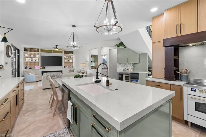 Open-concept kitchen featuring a large central island with an undermount sink, light-toned countertops, and a white range