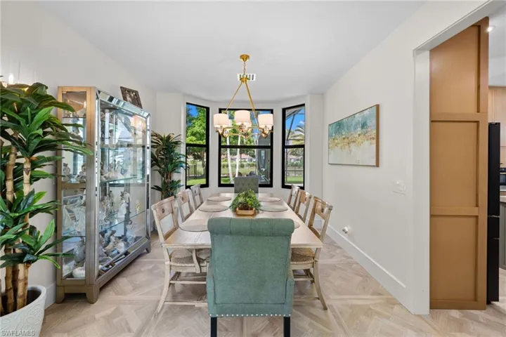 Dining area featuring a bay window, wood-finish flooring, white walls, and a contemporary chandelier