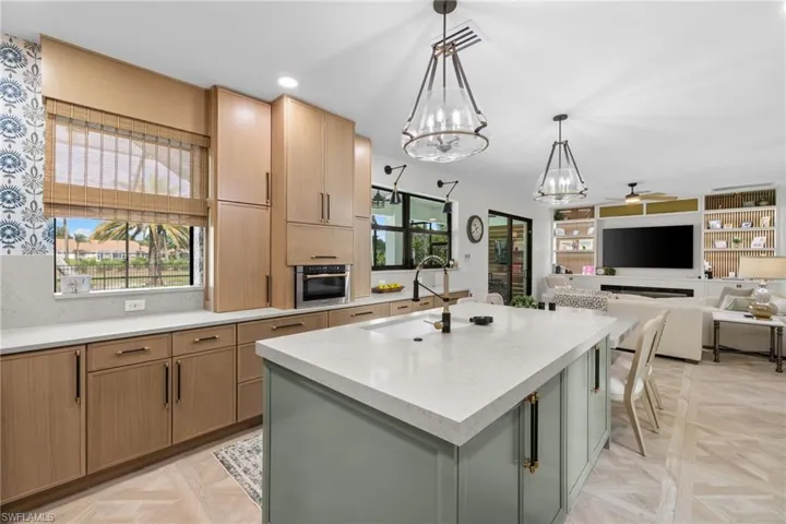 Open-concept kitchen and living area featuring a large center island with a light-colored countertop