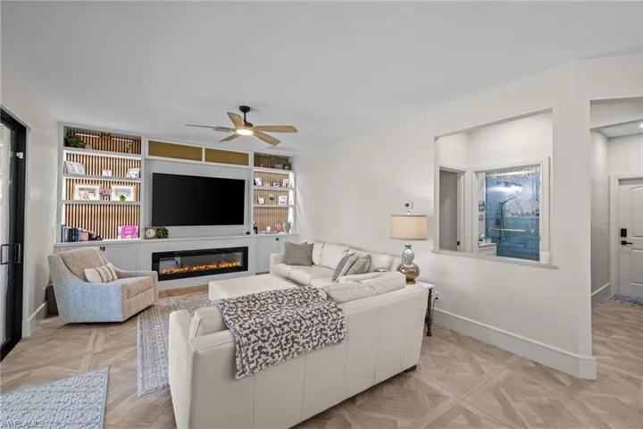 Living area featuring herringbone wood-finish flooring and a built-in media center with shelving