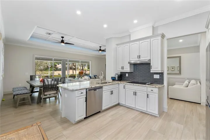 The open-concept kitchen features white cabinetry, granite countertops, and stainless steel appliances, including a dishwasher