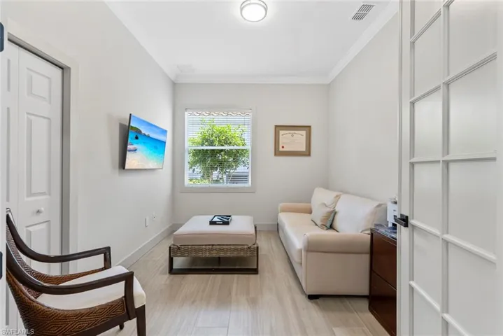 This room features light-colored walls, tile flooring, a window with blinds, and crown molding