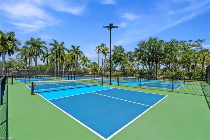 The property offers pickleball courts with a green and blue surface, surrounded by fencing and mature palm trees