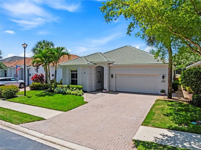 The property features a well-maintained lawn, a paved driveway, and a two-car garage