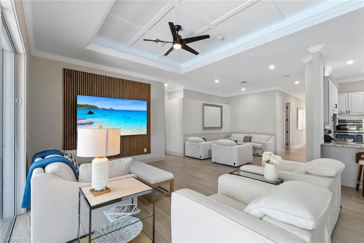 Spacious living area featuring light-toned flooring, a coffered ceiling with a ceiling fan, and recessed lighting