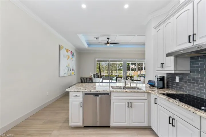 The kitchen features white cabinetry, granite countertops, a stainless steel dishwasher, and a grey tile backsplash