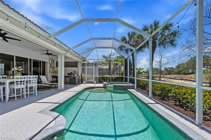 The property features a screened-in swimming pool and hot tub, complemented by a covered patio space with an outdoor dining table and ceiling fans