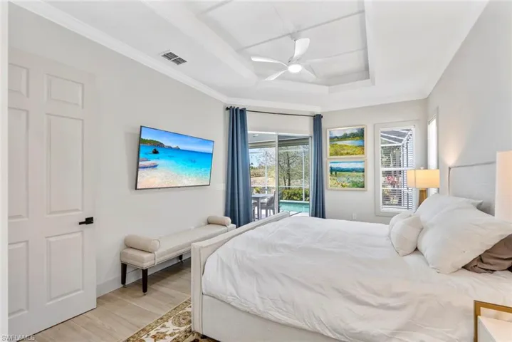 This room features a tray ceiling with a ceiling fan, a private outdoor space with a swimming pool, and large glass sliding doors and windows providing natural light