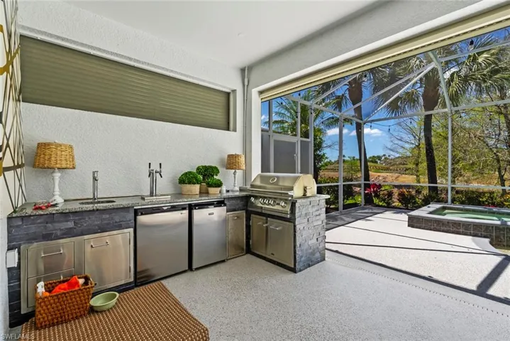This outdoor living area features a built-in grill, stainless steel appliances, a sink, and a hot tub