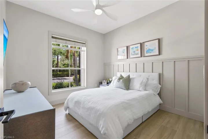 This room features light-toned flooring, a window offering views of greenery, and wainscoting along one wall