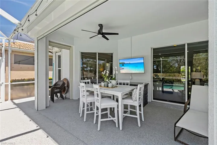 The property features a screened-in patio with a dining area, ceiling fan, and sliding glass doors