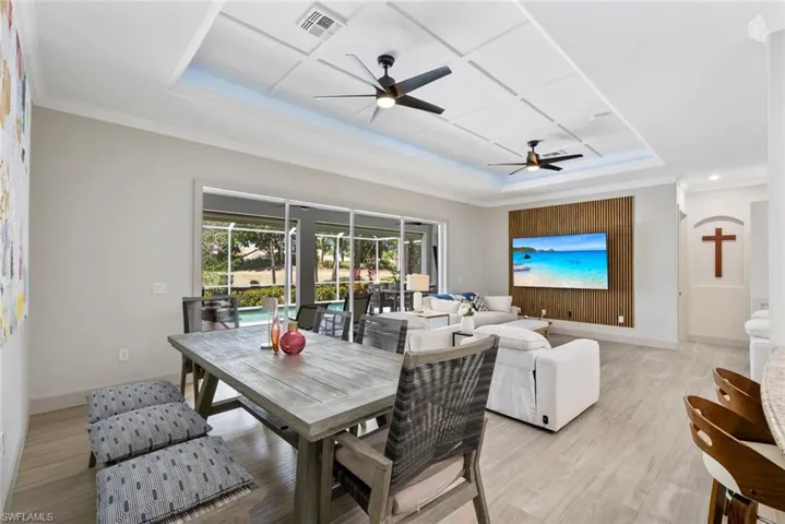 Open-concept living area with a coffered ceiling, ceiling fans, and light wood-look flooring