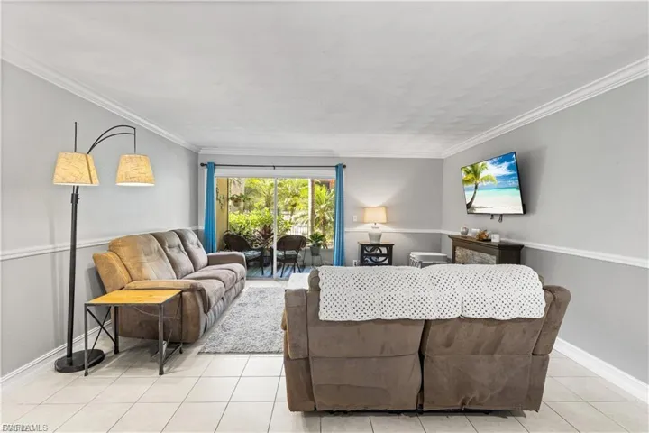 Living room featuring light tile patterned floors and crown molding