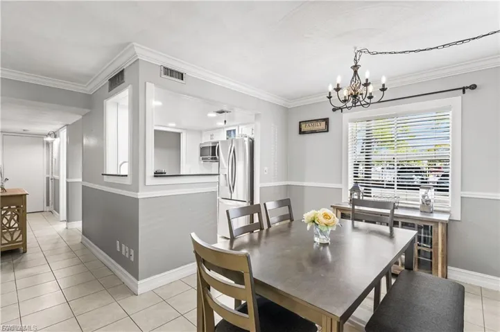 Dining room featuring light tile patterned floors, a chandelier, and crown molding