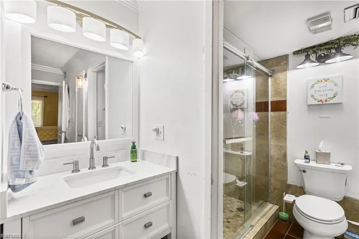 Bathroom featuring vanity, ornamental molding, and a shower stall