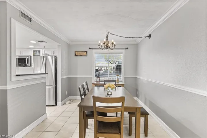Dining area with light tile patterned floors, a chandelier, and ornamental molding