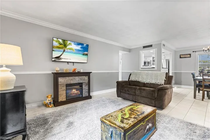 Living room featuring ornamental molding, a chandelier, tile patterned floors, and a fireplace