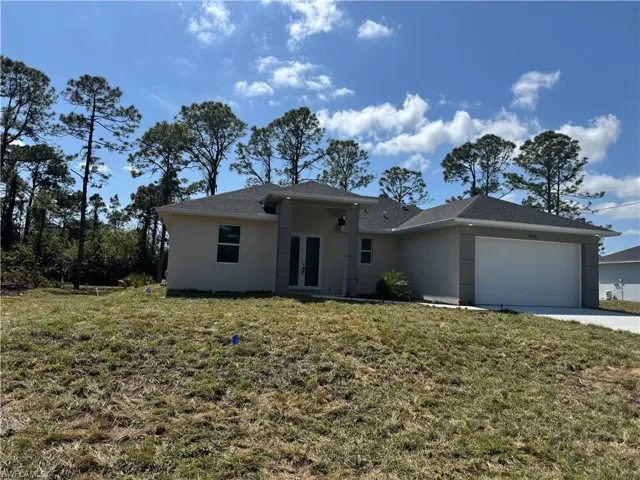 View of front of property with concrete driveway, a front yard, stucco siding, french doors, and a garage