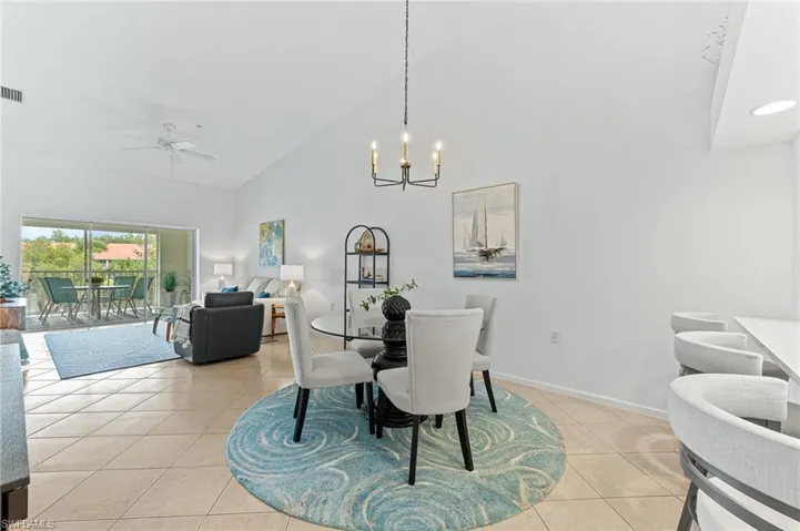 Dining area featuring high vaulted ceiling, ceiling fan, a chandelier, and light tile patterned flooring