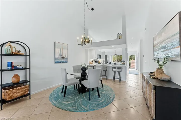 Dining space featuring light tile patterned floors, high vaulted ceiling, and a chandelier