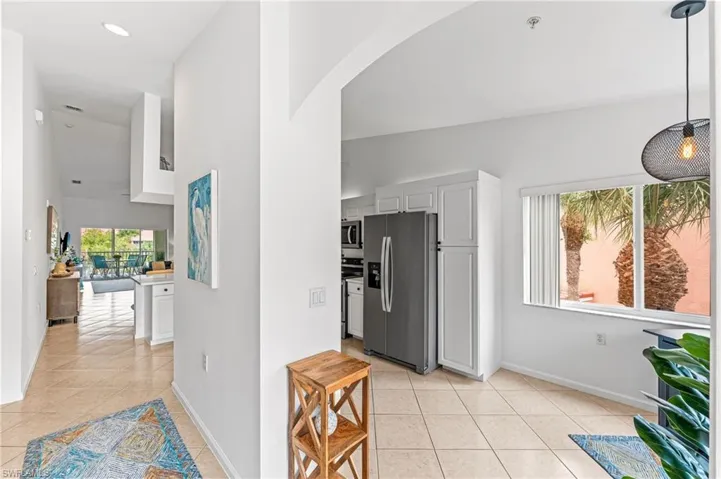 Kitchen featuring appliances with stainless steel finishes, white cabinetry, light tile patterned floors, and arched walkways