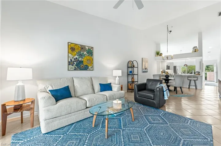 Living area featuring light tile patterned floors, high vaulted ceiling, and ceiling fan