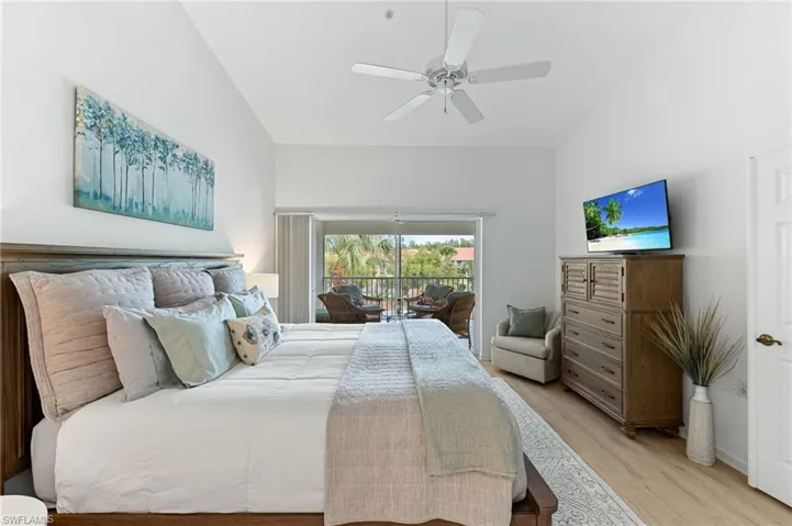 Bedroom with wood finished floors, lofted ceiling, access to exterior, and a ceiling fan