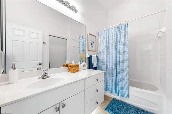 Bathroom featuring shower / bath combo, vanity, and light tile patterned floors
