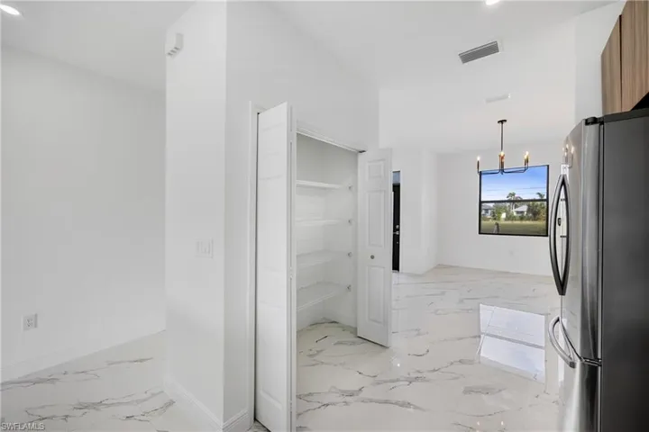 Corridor featuring a chandelier, light marble finish floors, and recessed lighting