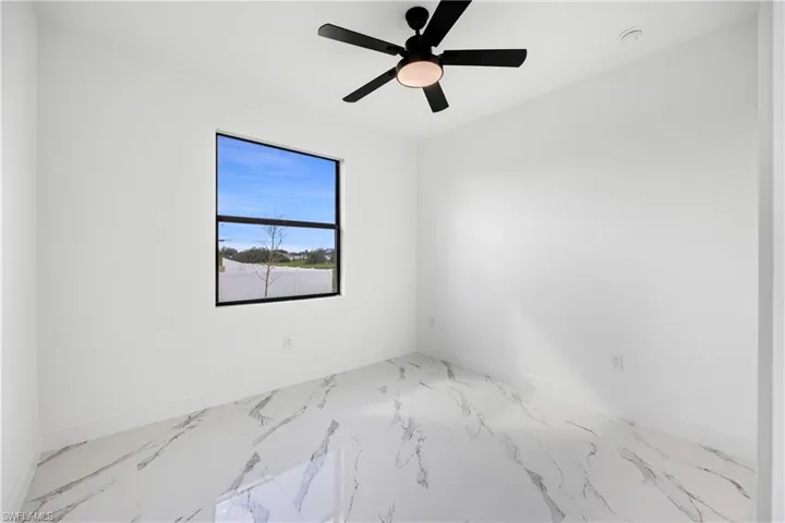Unfurnished room featuring marble finish floors and ceiling fan