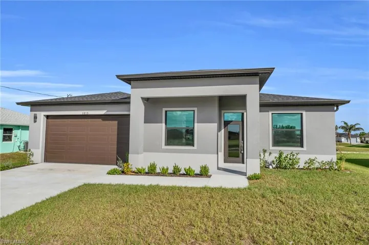 Prairie-style house featuring a front lawn, stucco siding, concrete driveway, and a garage