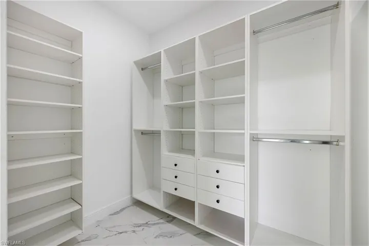 Spacious closet featuring light marble finish floors