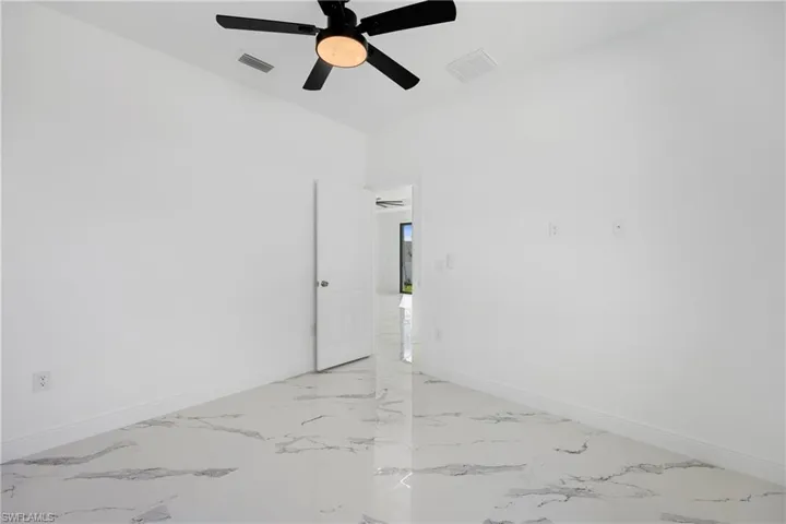 Empty room with light marble finish floors and a ceiling fan