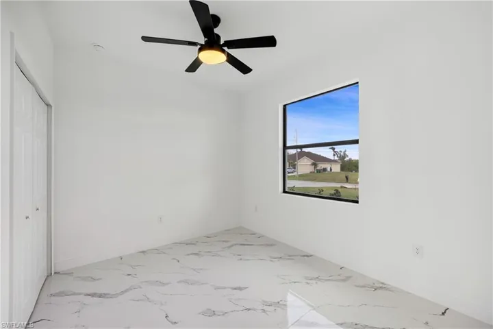 Unfurnished bedroom with light marble finish flooring, a closet, and ceiling fan