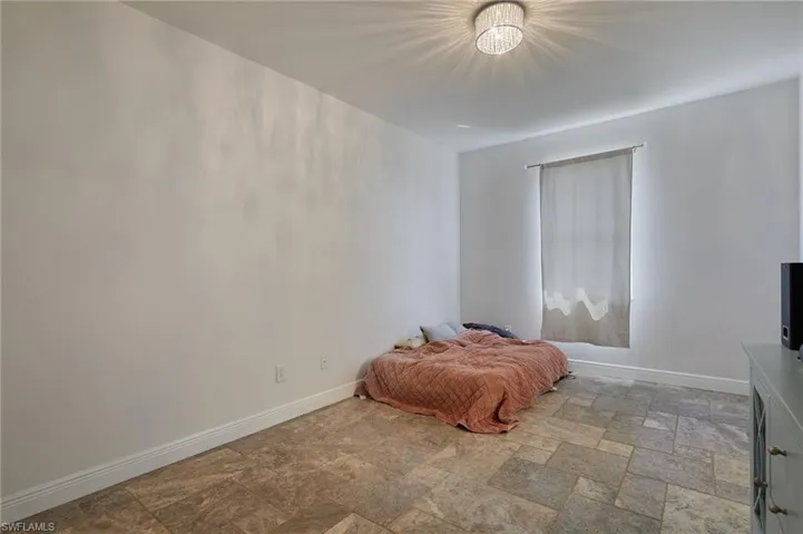 Bedroom featuring stone finish flooring and baseboards