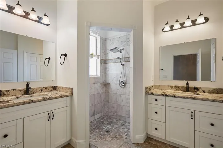Bathroom with a sink, walk in shower, and two vanities