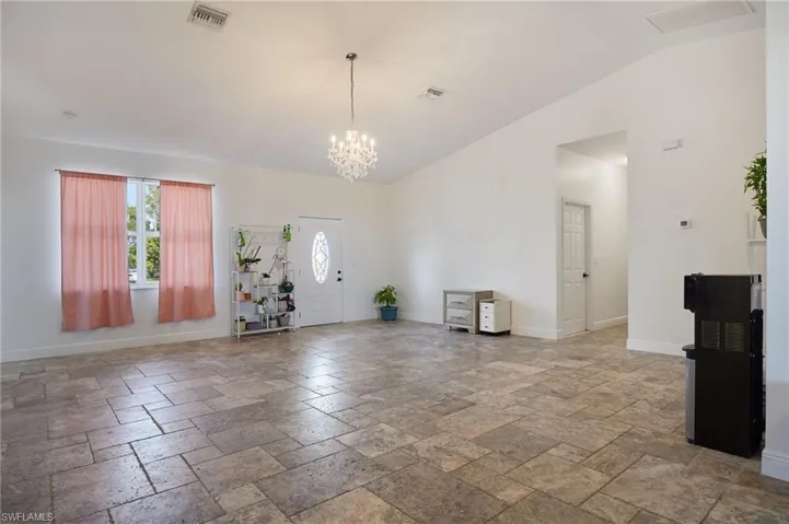 Foyer entrance with visible vents, baseboards, a chandelier, and stone tile floors