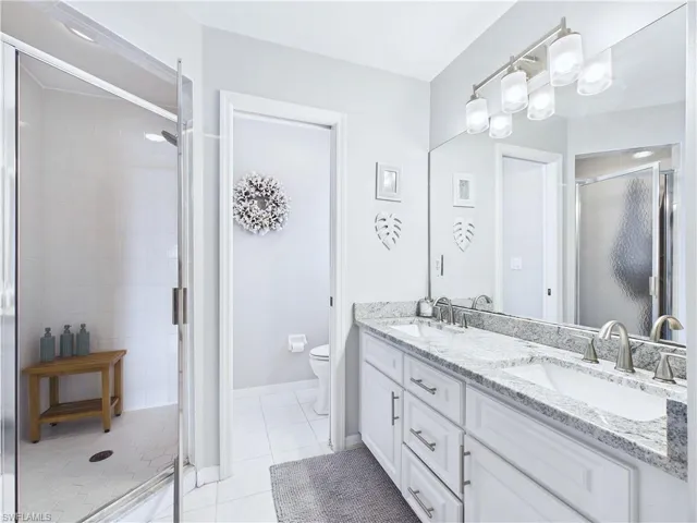 Dual Sinks with granite counter, a step in shower and a water closet