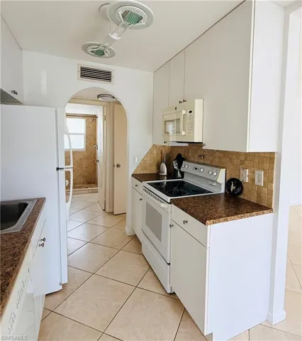 Kitchen featuring white cabinetry, brown speckled countertops, a mosaic tile backsplash, and diagonal tile flooring