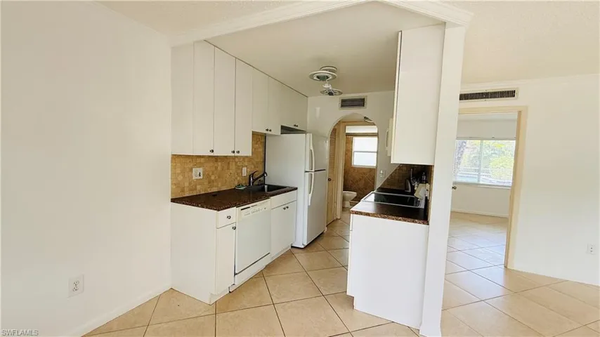 Kitchen featuring white cabinetry, brown speckled countertops, and a mosaic tile backsplash