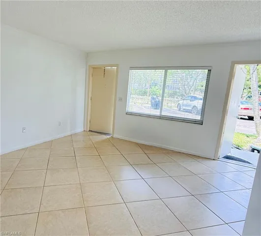 Light-toned tile flooring, white walls, and a large window with horizontal blinds