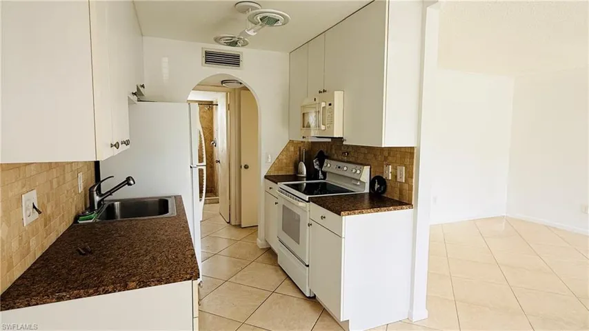Kitchen featuring white cabinetry, brown speckled countertops, and a tiled backsplash